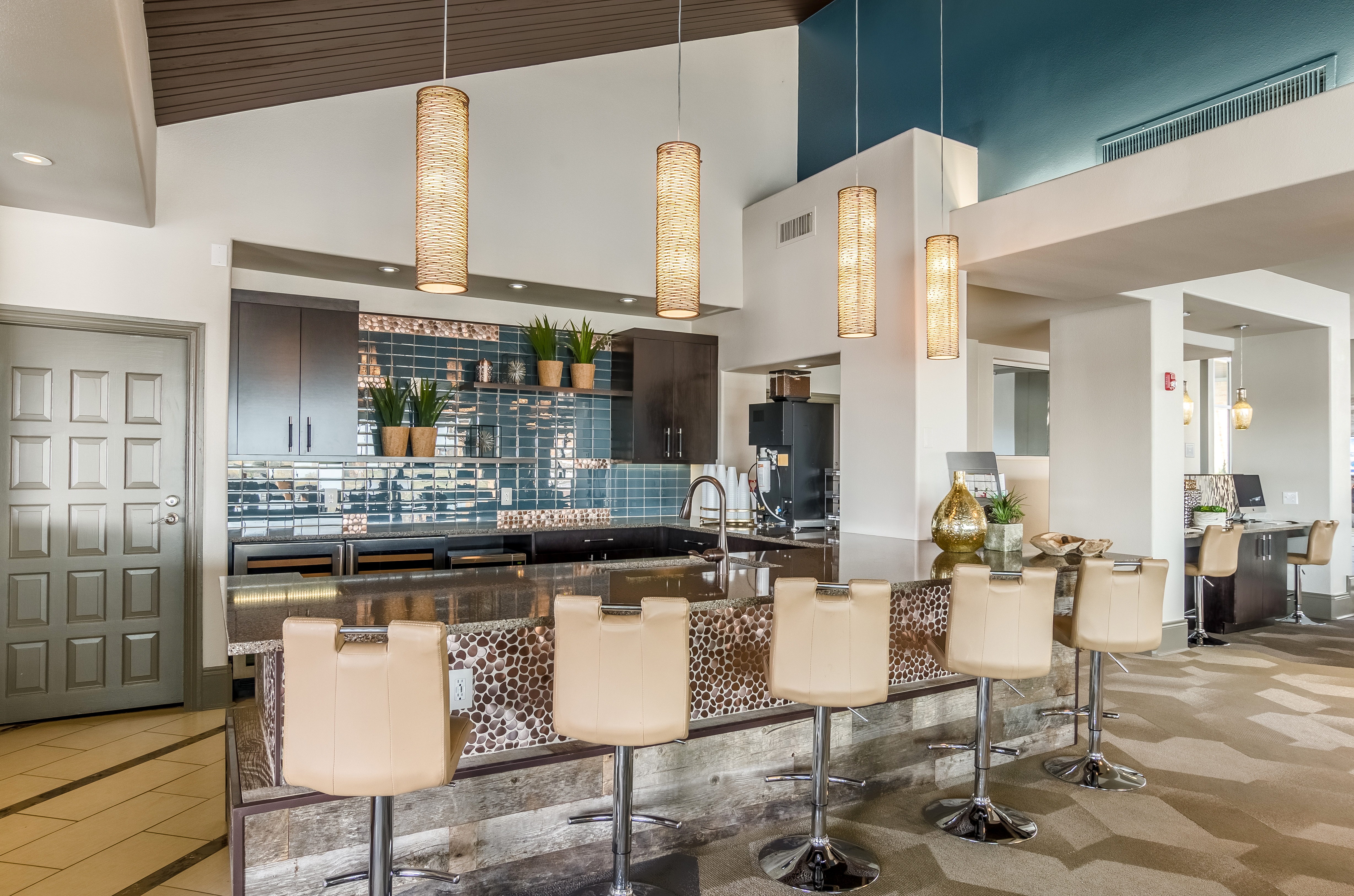 A modern kitchen with a bar area and chairs.